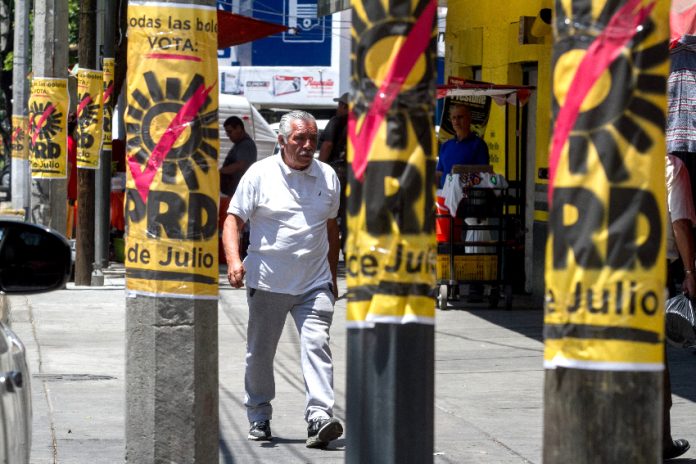 A man walks by PRD campaign posters on posts in Mexico City