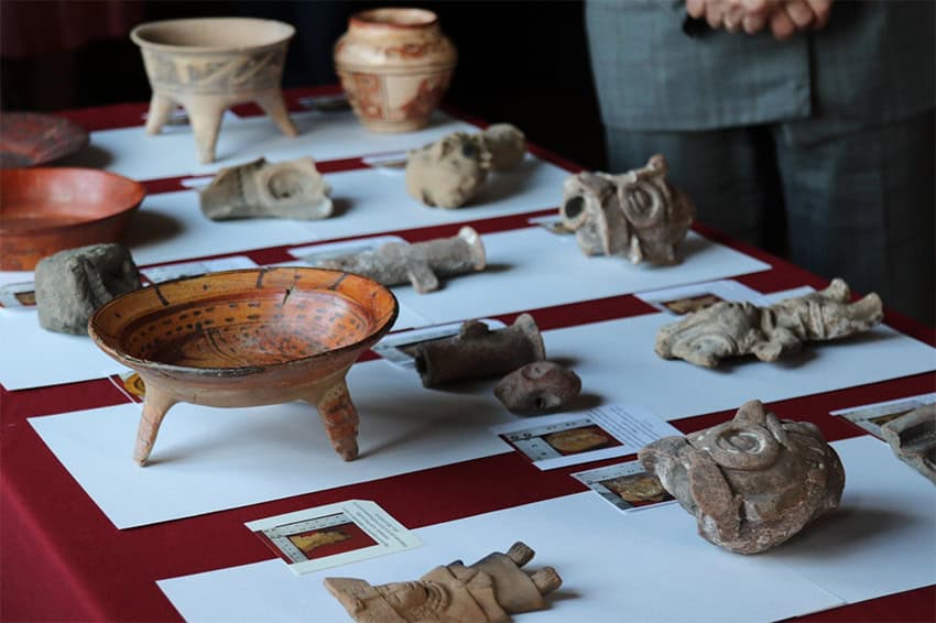 A Maya vase along with other clay pottery and stone masks made by ancient Indigenous people in Mexico.