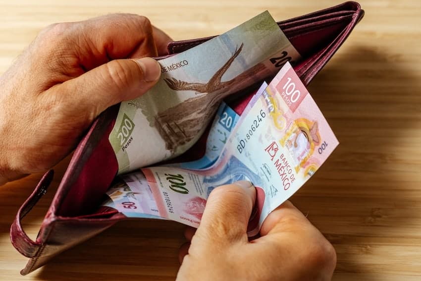 Hand taking Mexican money out of a wallet